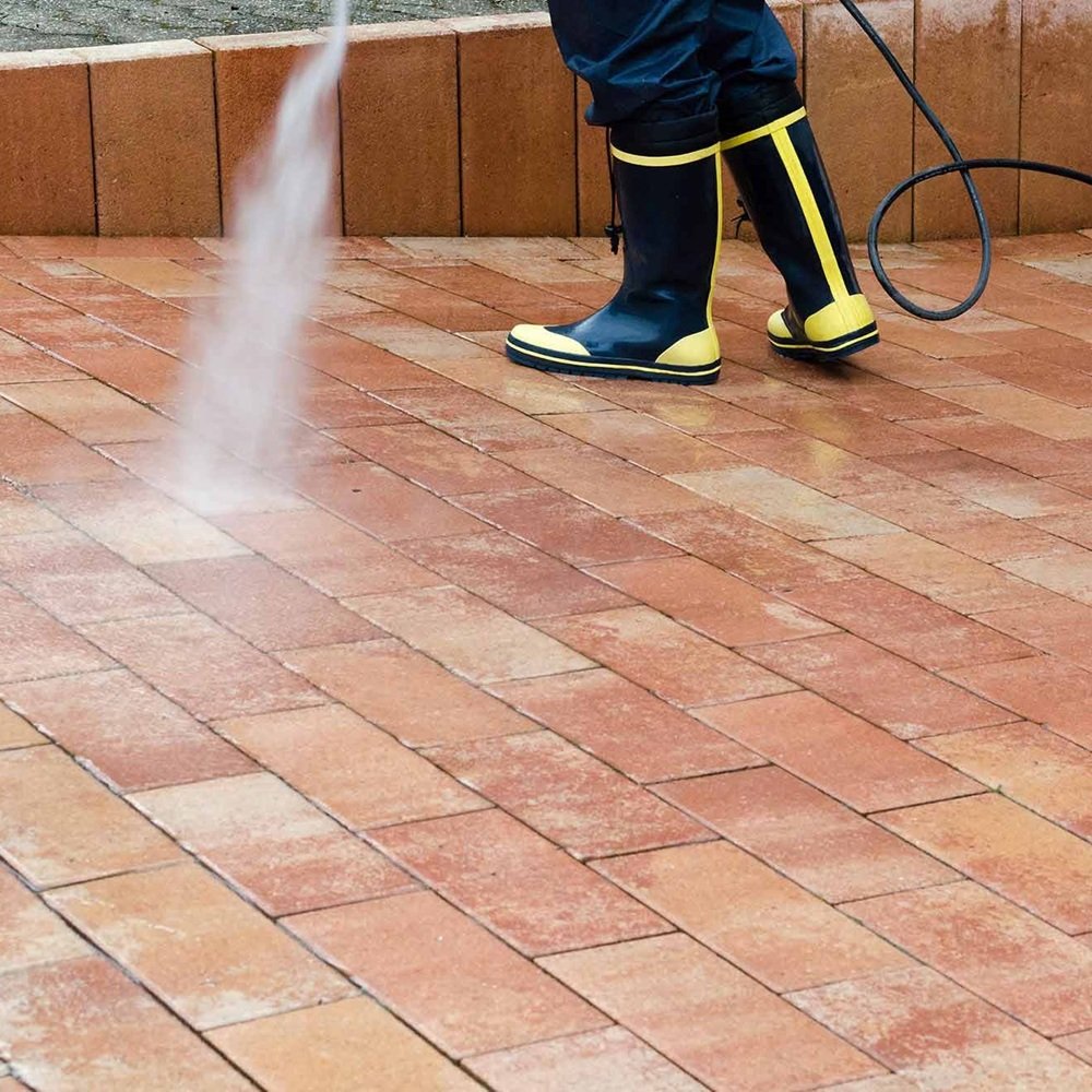 Freshly cleaned brick paver patio beside outdoor dining area after heavy surface staining removal