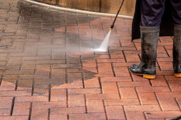 Brick paver patio being professionally cleaned to remove dirt, weeds, and surface stains.
