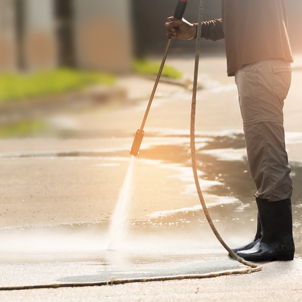 Experienced cleaner removing dark buildup from heavily used residential concrete walkway with precision