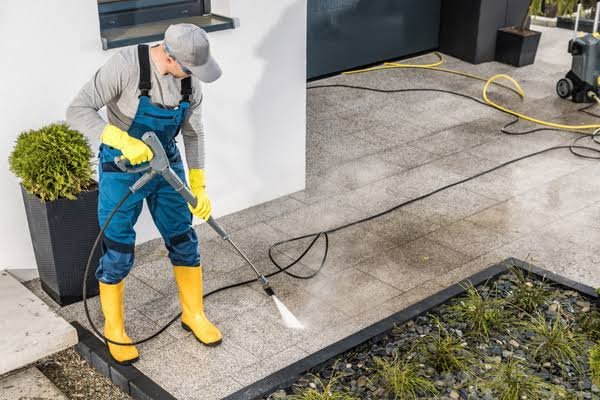 Concrete patio being pressure washed to remove years of dirt and built-up stains.