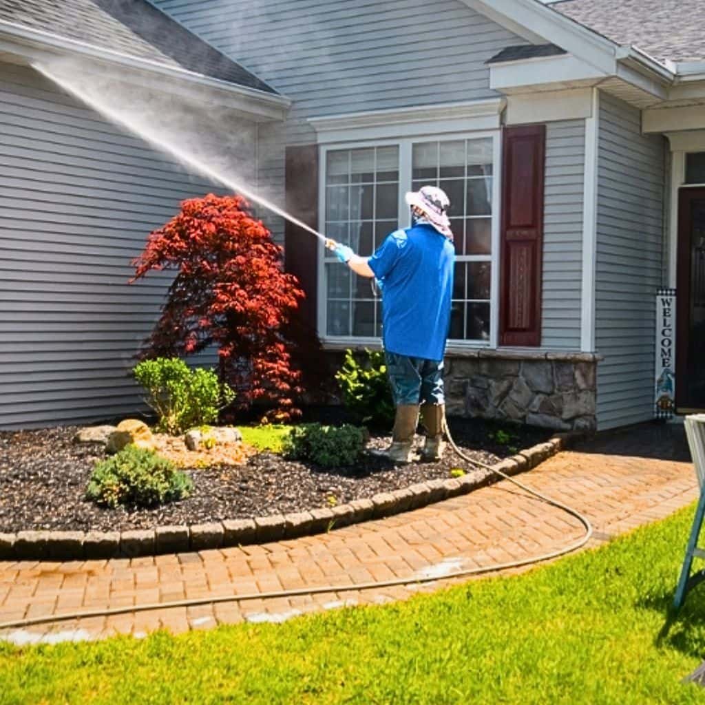 Technician soft washing algae-stained siding on a suburban Washtenaw County home exterior